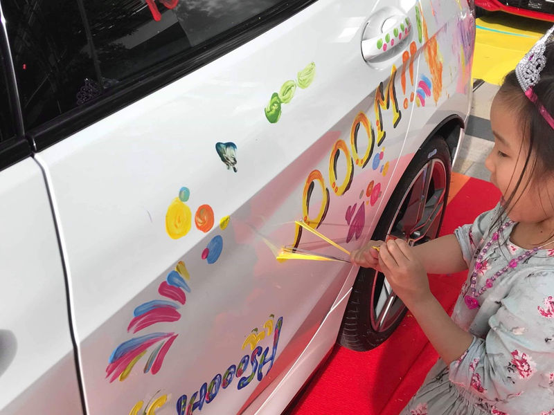 子どもがBMWの車体に指で描いている