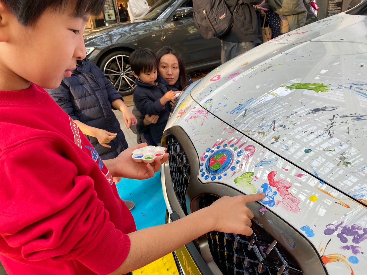 BMWの車体に指で描く子どもたち