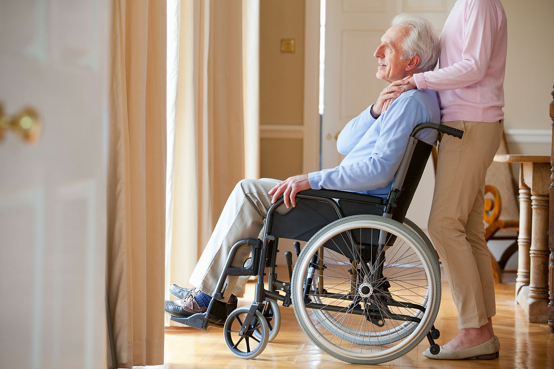 A woman in a wheelchair smiles while conversing with an elderly man