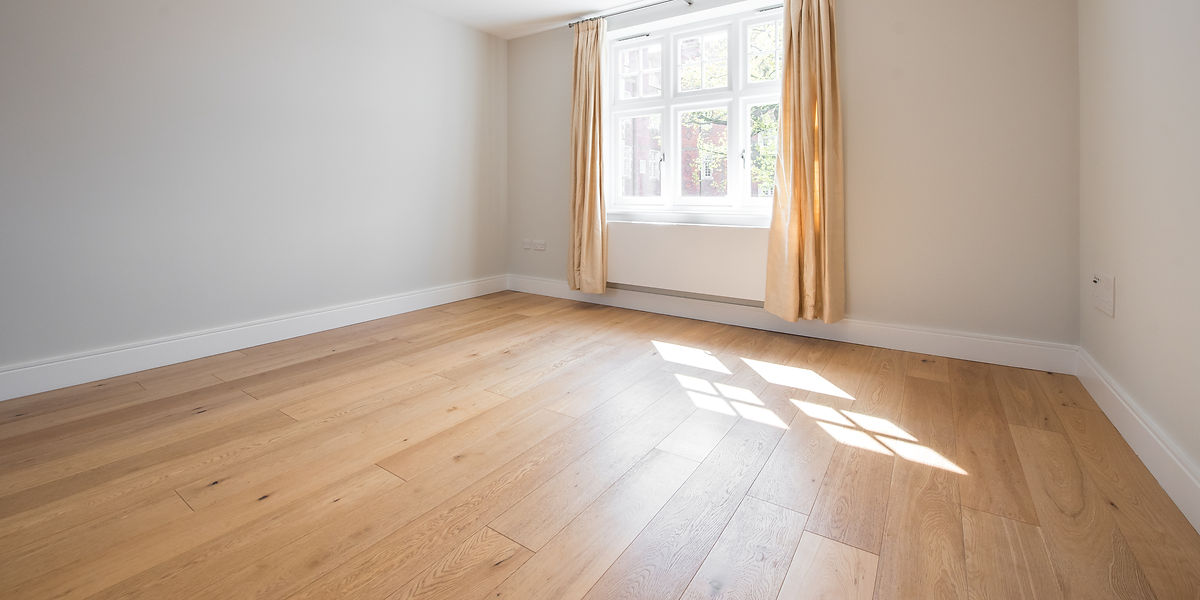 Sunlit empty room with light wood flooring