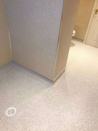 Speckled grey flooring meets a beige wall corner