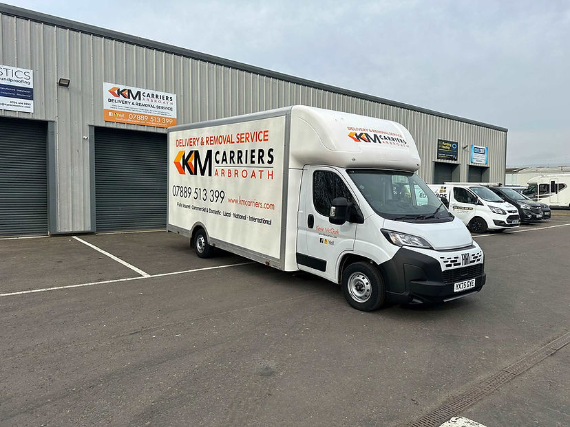 White delivery van with "KM Carriers Arbroath" branding parked at an industrial site