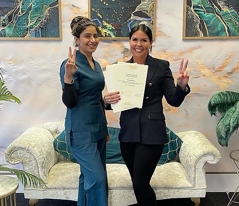 Two women stand smiling and holding certificates