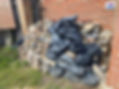 Pile of bricks and black plastic bags stacked against a red brick wall
