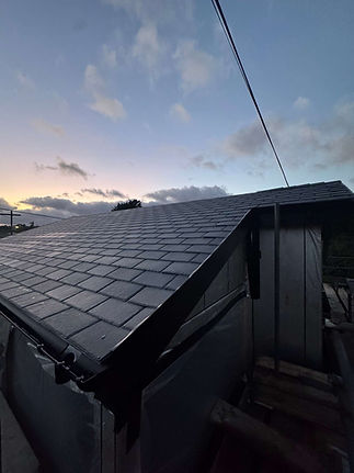 Slate roof with chimney and guttering photographed at dusk