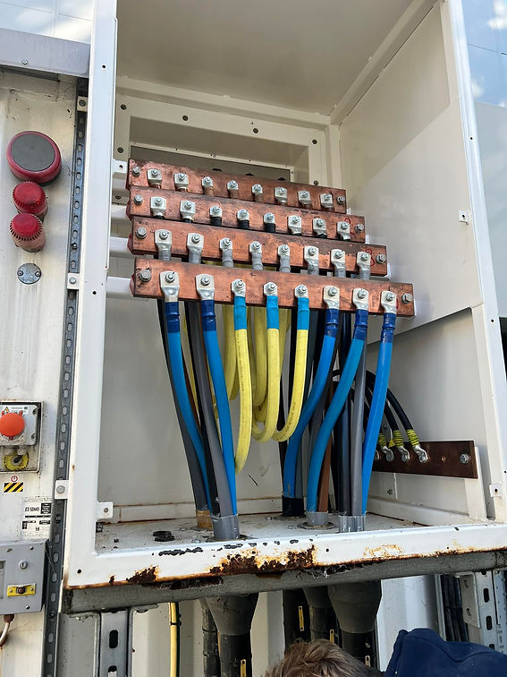 Close-up of an electrical panel showing copper busbars with multiple blue and yellow cables attached
