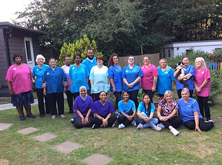 A diverse group of care workers in blue and pink uniforms