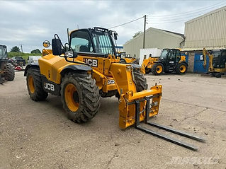 A JCB telehandler with a forklift attachment parked in a space