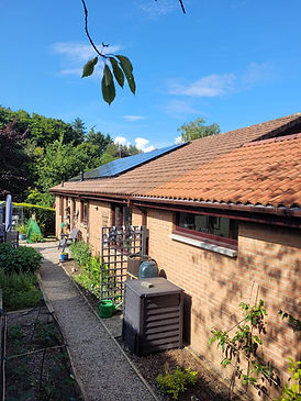 A brick house with a red-tiled roof and solar panels