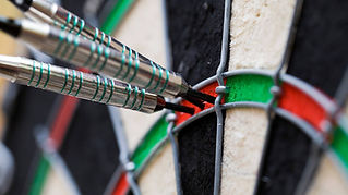 Close-up image of two darts hitting the bullseye of a dartboard