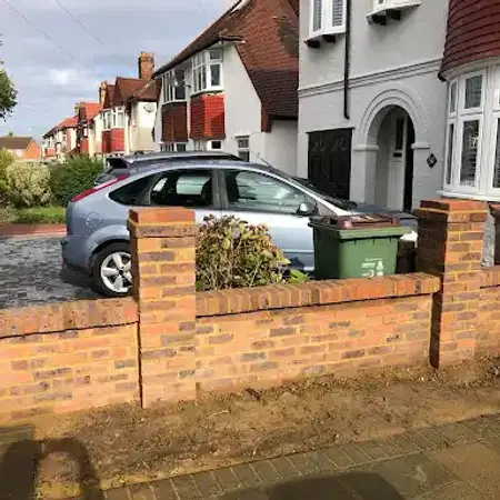 A newly built low brick wall in front of a paved driveway