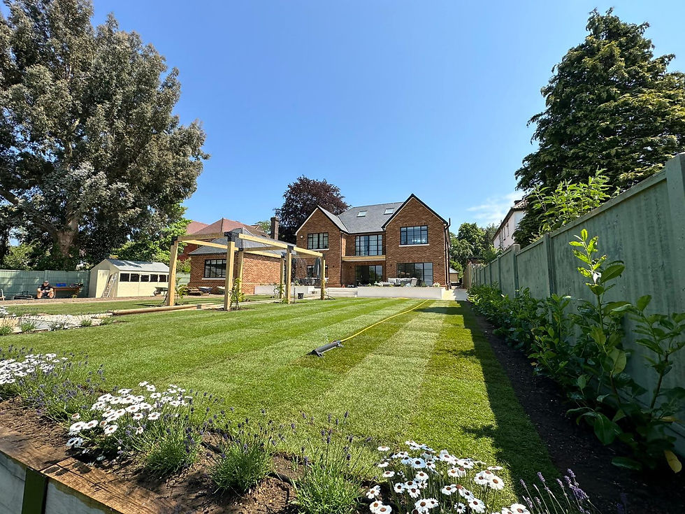  A spacious, landscaped garden with a freshly striped lawn and a large brick house in the background