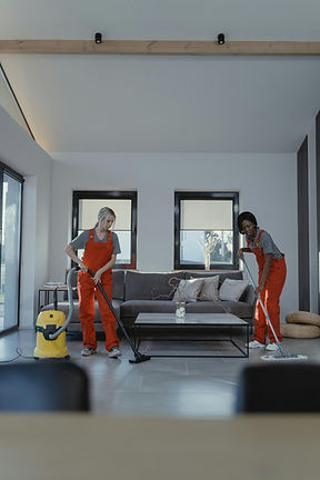 Two people in orange overalls clean a modern living room