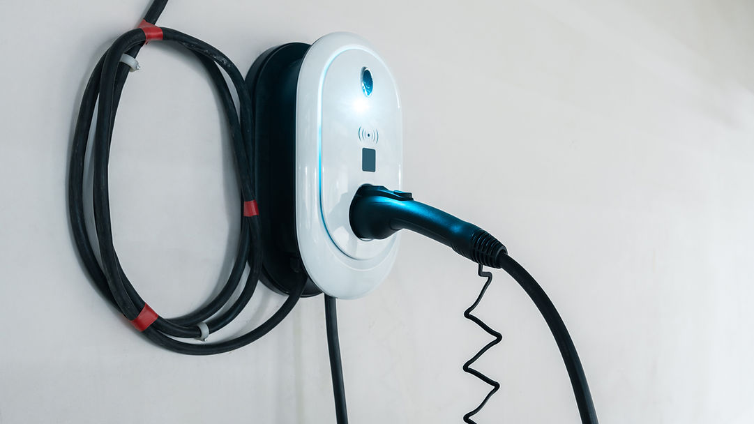 Wall-mounted electric vehicle charging station with a glowing indicator and coiled cable