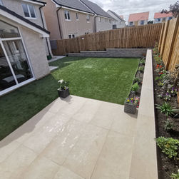 Modern back garden with tiled patio, lush green lawn