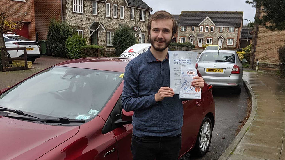 Man holding an automatic driving test pass certificate next to a red car