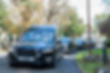 A cortege with two black hearses driving through a graveyard.