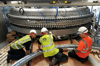 Three construction workers inspect large industrial machinery