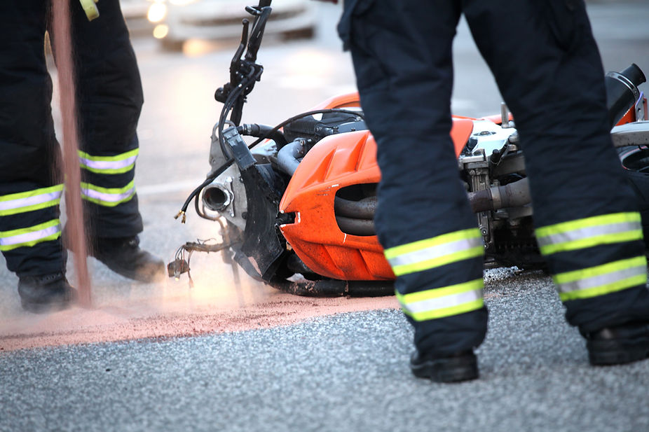 First responders at the scene of a motorcycle accident, with a fire extinguisher being used.