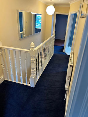 A hallway with blue carpet and cream walls
