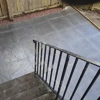 Stone patio stairs lead down to a slate-tiled yard