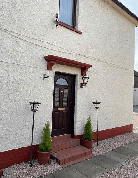 The image shows the exterior front entrance of a house featuring light-coloured textured pebble-dash walls