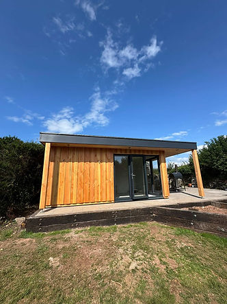 Timber-clad garden room with glass doors set against a blue sky