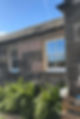 The image displays a rustic stone cottage featuring traditional wooden sash and case windows with white frames set