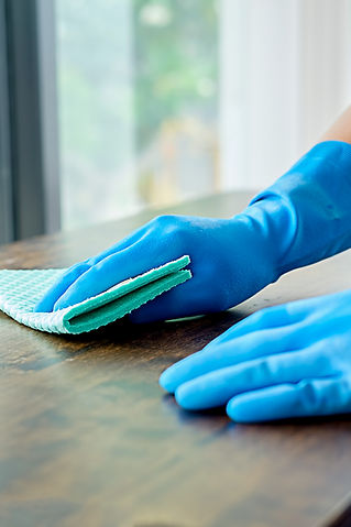 A person wearing blue gloves is cleaning a wooden surface