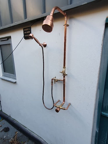 A new outdoor copper shower with a large rain head and a smaller handheld shower head