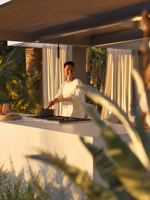 Person cooking in a luxury Miami outdoor kitchen surrounded by tropical landscaping and warm evening light, enjoying a beautifully designed South Florida backyard made for relaxing, entertaining, and everyday outdoor living.