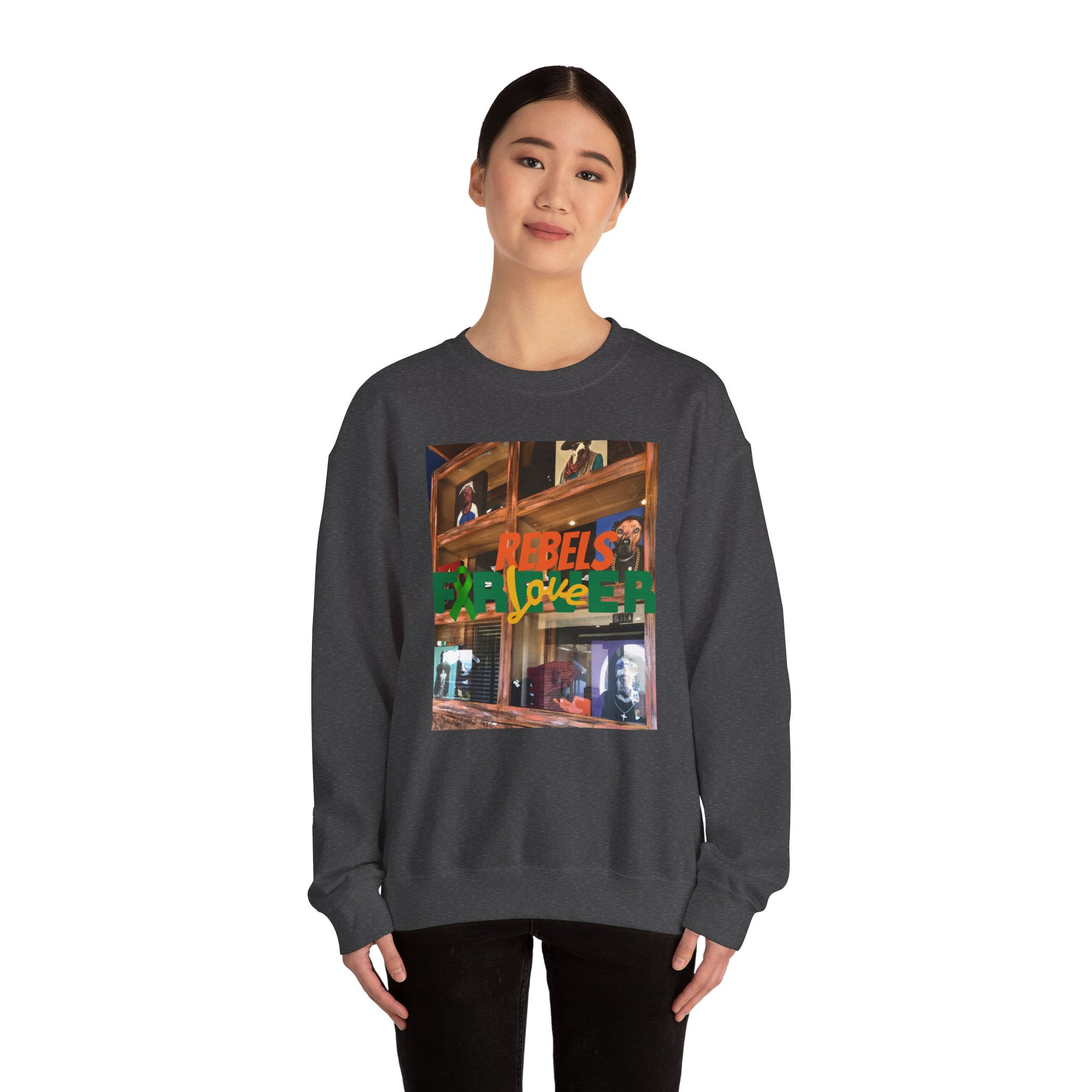 A person wears a dark-colored sweatshirt featuring a vibrant collage-style graphic on the front. The design blends warm-toned