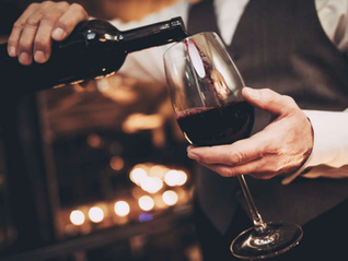waiter pouring red wine in a wine glass
