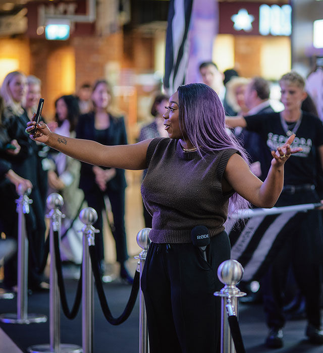 Woman taking a selfie at Sephora’s Bluewater opening event, standing on a black carpet with an audience in the background.