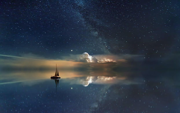 Sailboat on calm waters with stars reflecting on the water