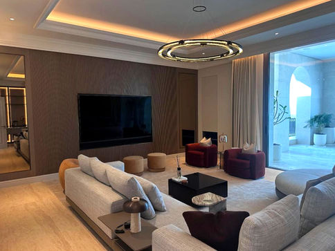 Luxury living room with a wall-mounted display, cove lighting and pool view, fully integrated by Signature