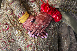 Mehndi bride’s henna hands holding wedding rings for close-up detail in London