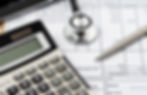 A calculator, stethoscope, and pen on top of a medical bill