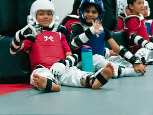 Smiling Team One Taekwondo kids in sparring gear taking a break during class in McAllen, TX