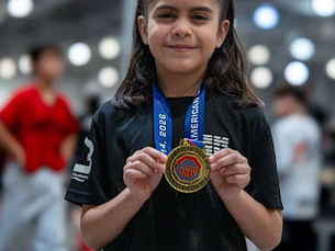 Young Team One Taekwondo student in McAllen, TX proudly holding a competition medal