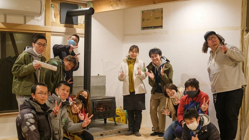 薪ストーブの周りに集まる人々の画像