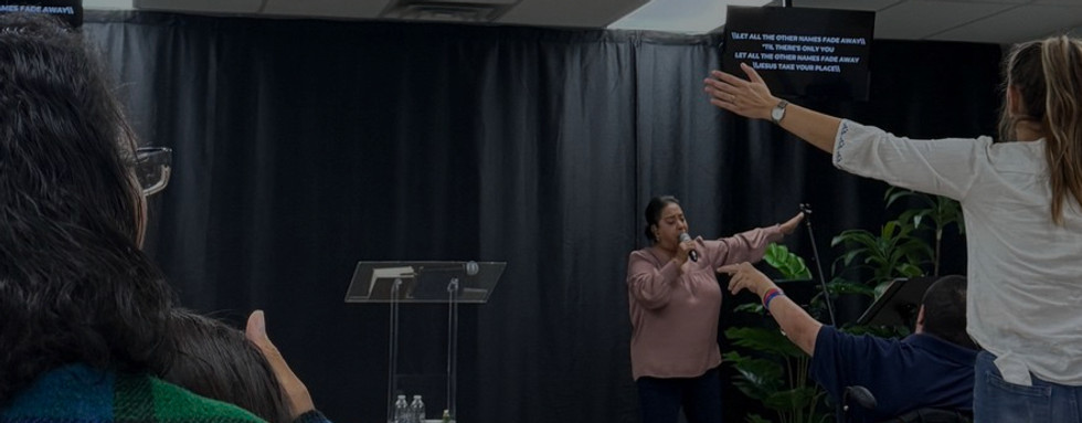 Congregation worshipping together during a service at Compassion Church Albuquerque with raised hands and live worship music.