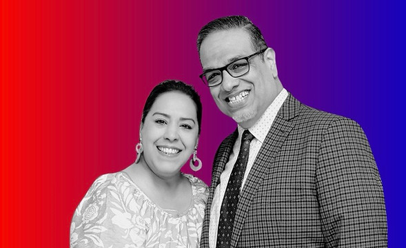 Smiling pastoral couple posing together against a colorful red and blue gradient background.