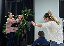 Woman leading worship while attendees pray and worship during a service at Compassion Church Albuquerque.