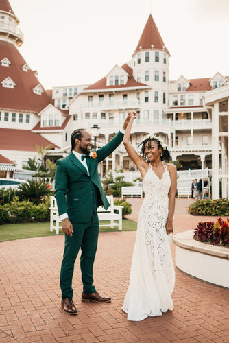 groom smiling at bride as she spins dancing with hotel del Coronado in the background.