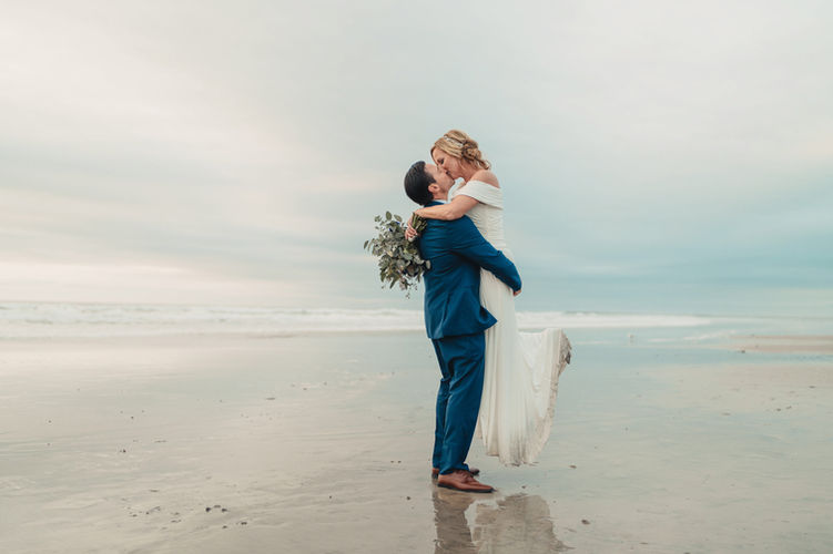 groom lifting bride on the beach in oceanside