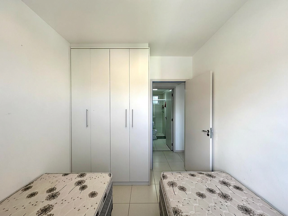 Quarto claro com dois colchões e guarda-roupa embutido branco