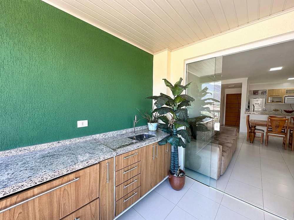 Varanda gourmet com parede verde e bancada