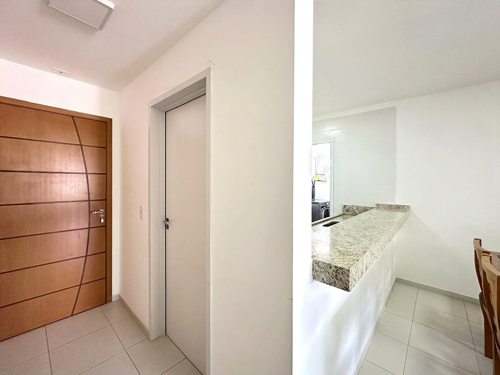 Hall de entrada com porta de madeira e balcão de cozinha em granito