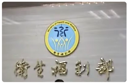 台湾の衛生福利部。灰色の壁に青黄の円形ロゴと金色の台湾語看板文字が並ぶ、静かな施設の外観。